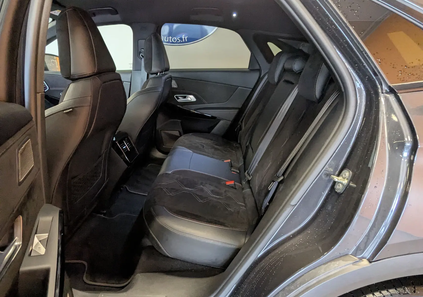 Vue intérieure côté droit montrant la banquette arrière en Alcantara noir du DS7 gris laqué avec portes ouvertes.