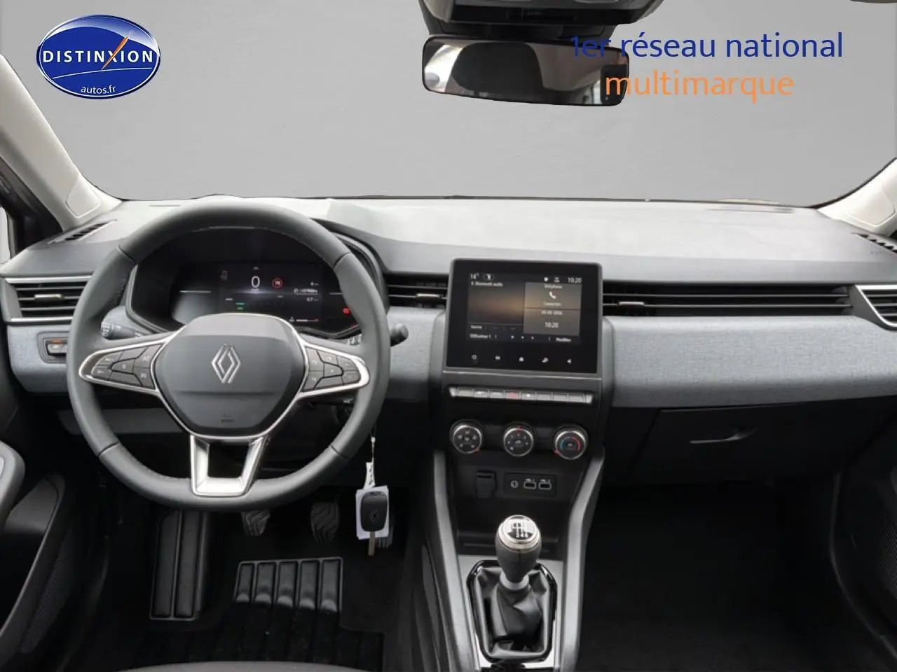 Vue intérieure avant du tableau de bord de la Renault Clio V gris schiste avec volant multifonction et écran tactile central.