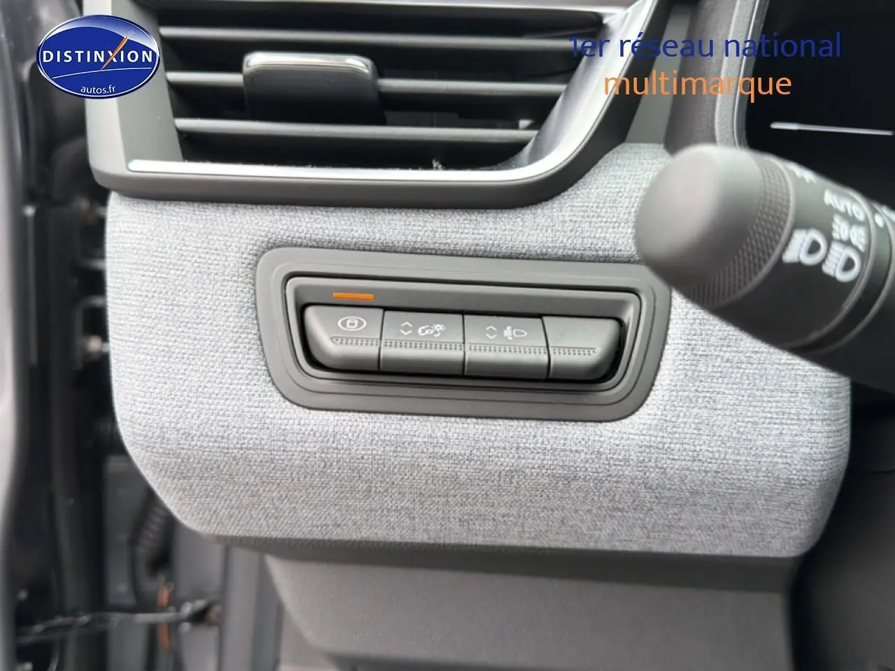 Détail des commandes d’éclairage sur tableau de bord gris clair d’une Renault Clio V 1.0 TCe 90 essence.