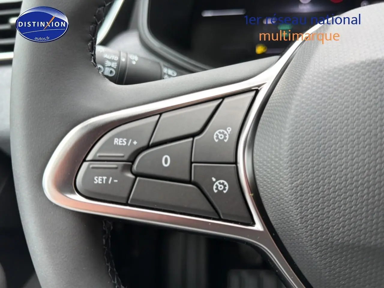 Gros plan sur les commandes de régulateur de vitesse au volant d'une Renault Clio V gris schiste, intérieur moderne.