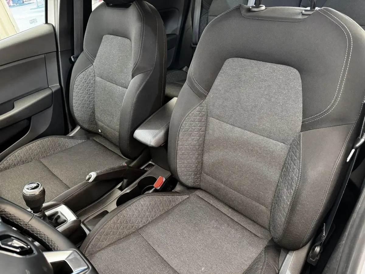 Vue intérieure rapprochée des sièges avant gris foncé de la Renault Clio Business TCe 90 avec levier de vitesse manuel visible.