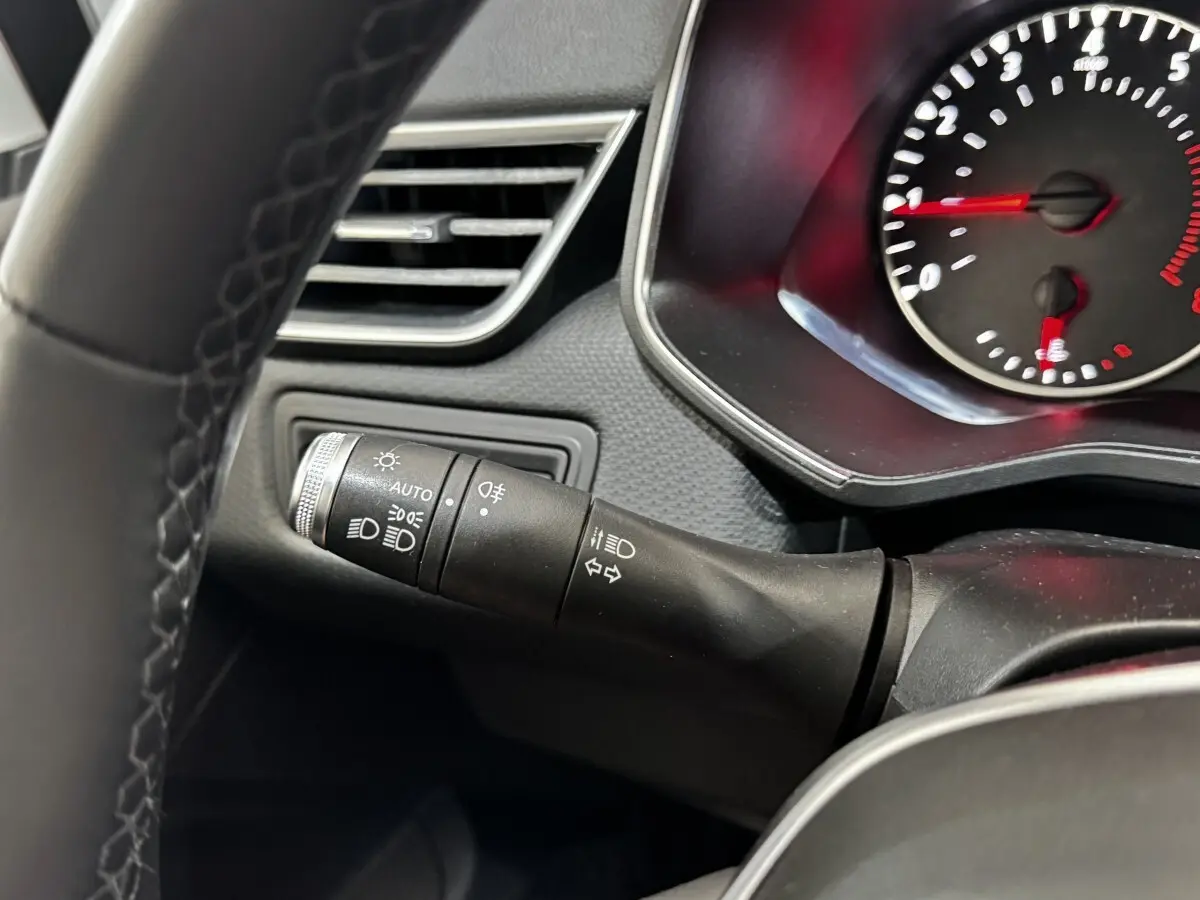 Gros plan sur la manette de commandes des phares et clignotants dans l’habitacle gris foncé de la Renault Clio Business TCe 90.
