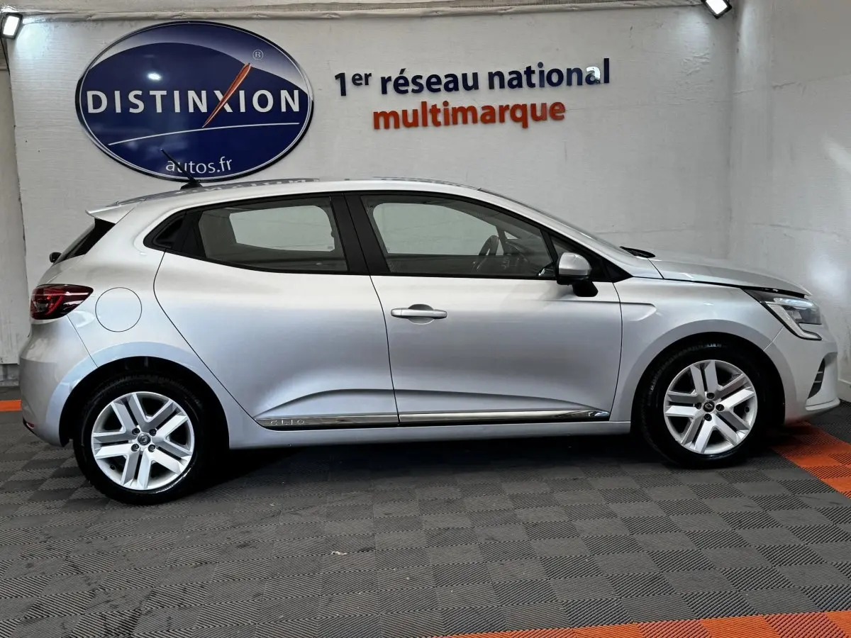 Profil côté gauche d'une Renault Clio Business TCe 90 gris clair 2020, avec jantes alliage et poignées de porte chromées.