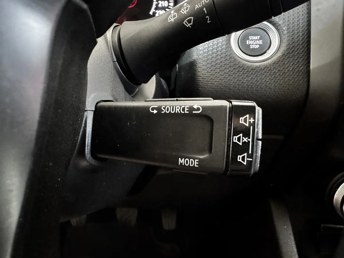 Gros plan sur la commande multifonction noire côté gauche du volant d’une Renault Clio gris clair 2020 avec bouton Start Engine Stop visible.