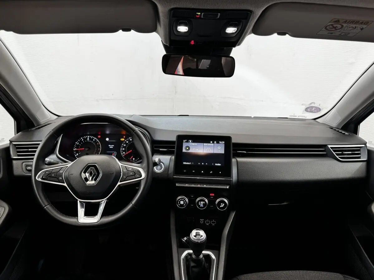 Vue frontale de l'intérieur de la Renault Clio Business TCe 90 2020, tableau de bord noir avec écran tactile central et volant cuir.