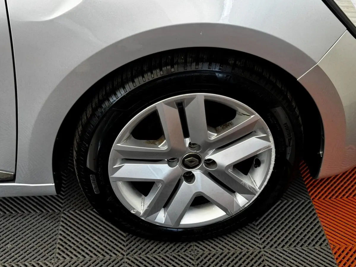 Gros plan sur la roue avant droite gris clair d'une Renault Clio Business TCe 90 2020 avec jante alliage et logo Renault central.