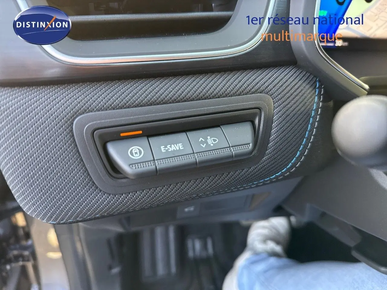 Gros plan sur les commandes E-SAVE et réglage des phares dans l’habitacle gris cassiopée métal du Renault Symbioz 2024.