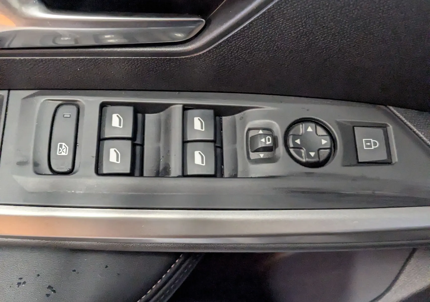 Vue rapprochée des commandes de lève-vitres et rétroviseurs sur la porte côté gauche d’un Peugeot 3008 noir 2025.