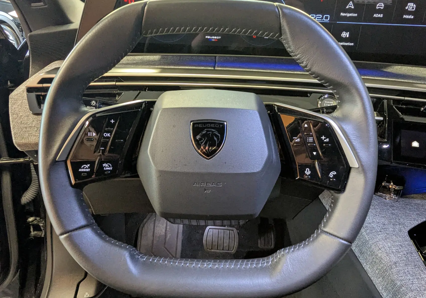 Vue rapprochée du volant cuir noir du Peugeot 3008 Hybrid 145 avec commandes intégrées et tableau de bord digital.