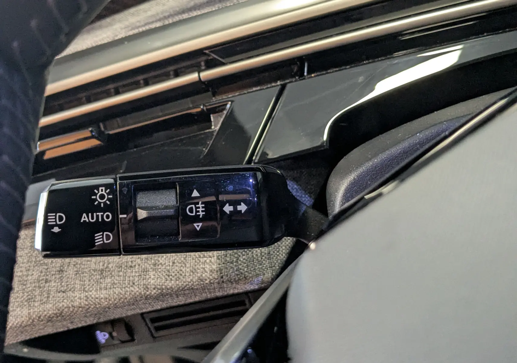 Gros plan sur la commande des feux du Peugeot 3008 noir, avec détails des symboles d’éclairage et finition intérieure tissu gris.