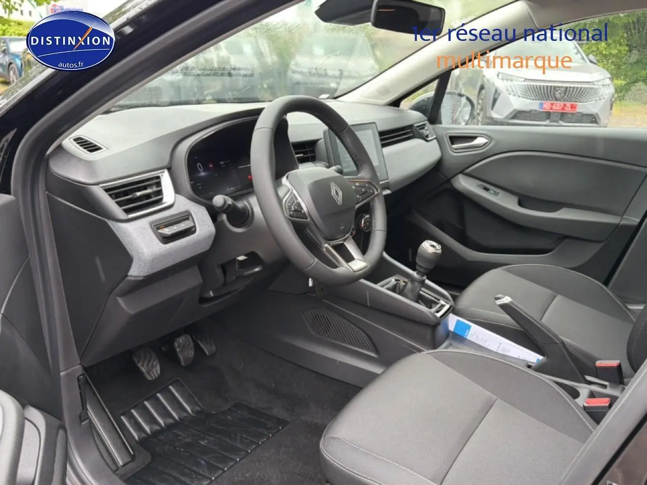 Intérieur avant droit de la Renault Clio V noire 2026, volant multifonction et boîte manuelle visibles.