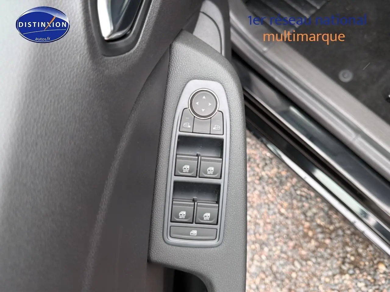 Gros plan sur les commandes des vitres électriques côté conducteur d'une Renault Clio V noire, avec porte ouverte.
