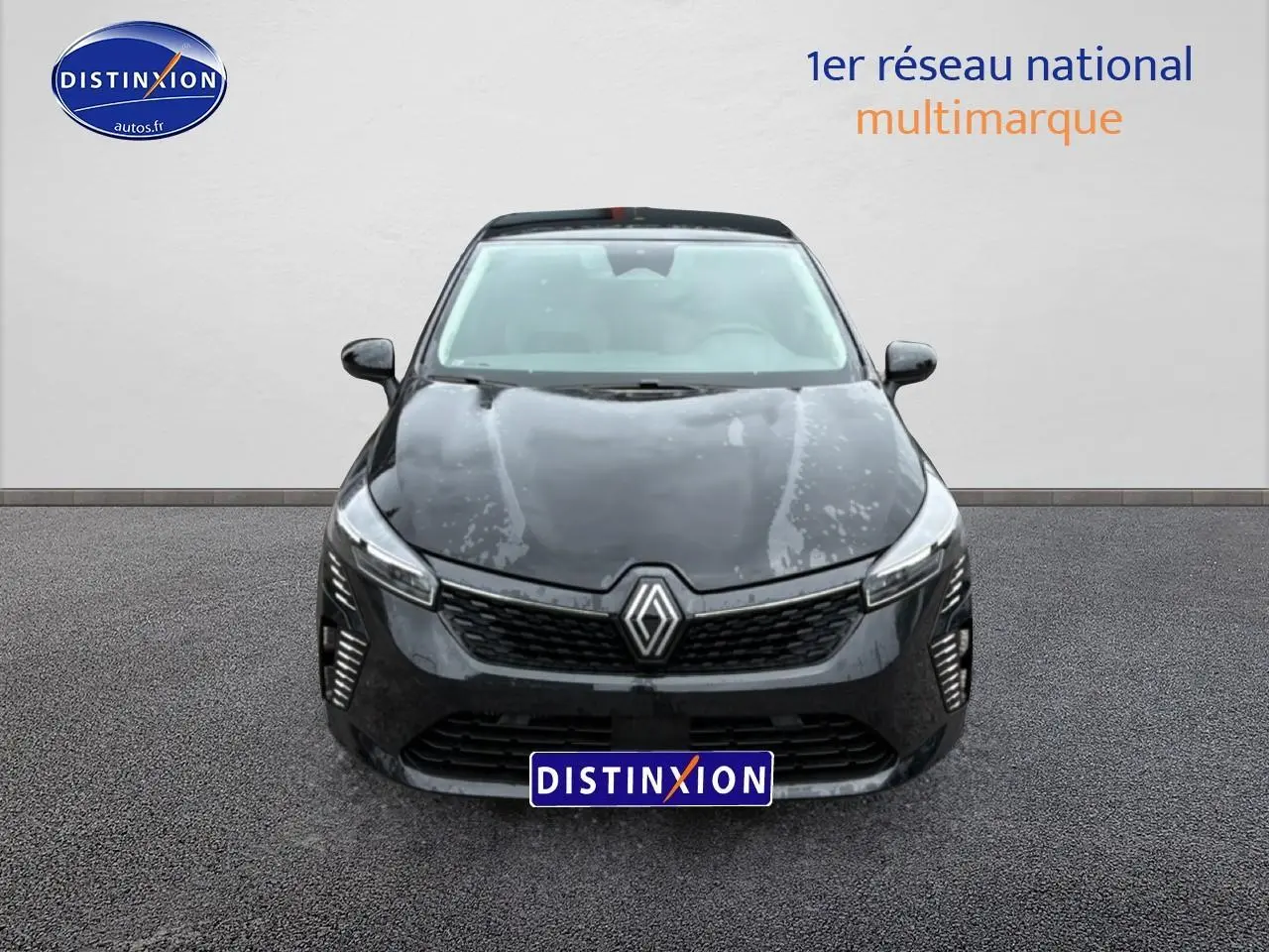 Renault Clio V noire vue de face, avec calandre distinctive et feux LED allumés sur un fond neutre.