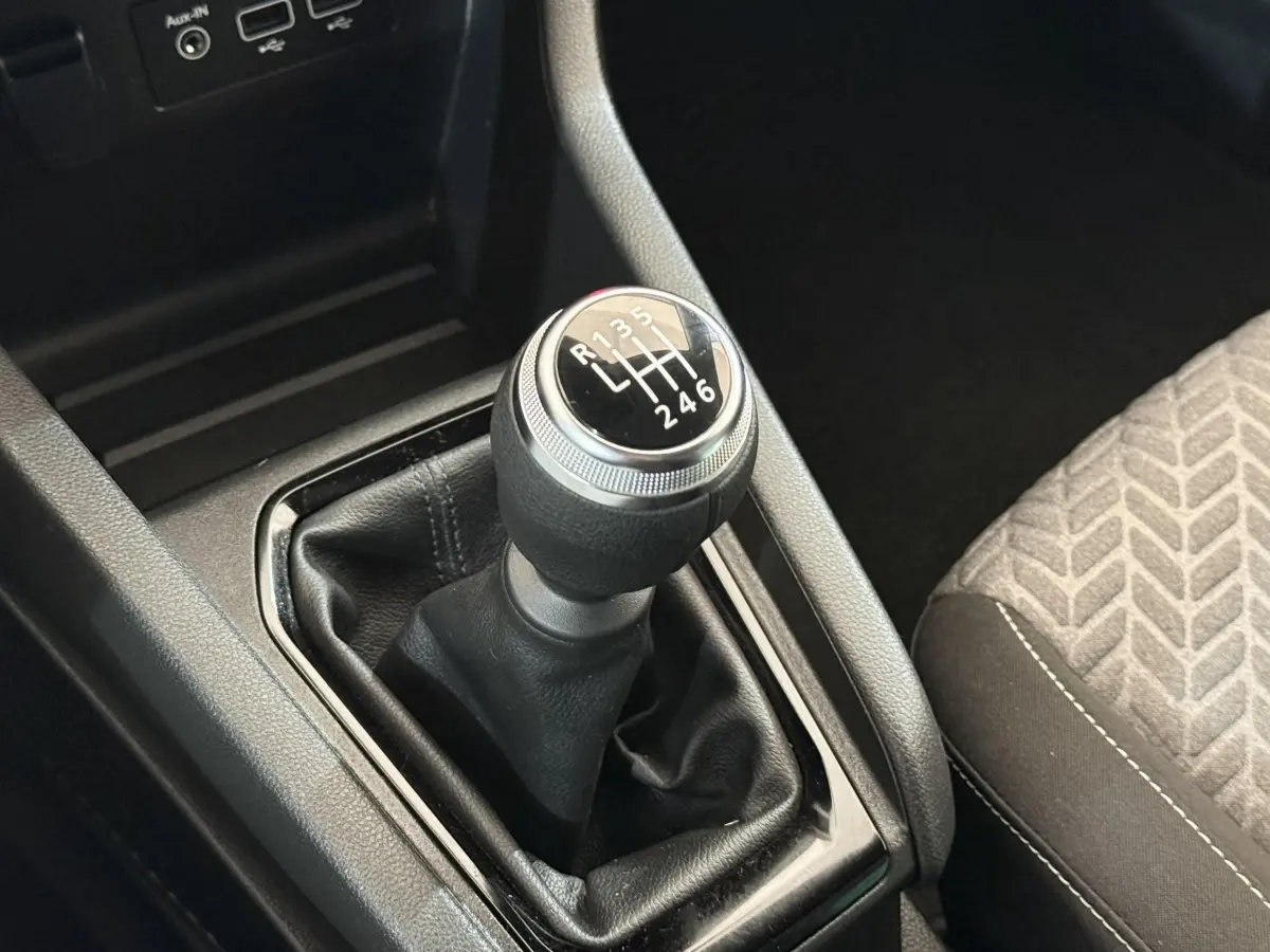 Le levier de vitesses manuel noir de la Renault Clio Evolution TCe 100 GPL, avec la console centrale et siège tissu visible.