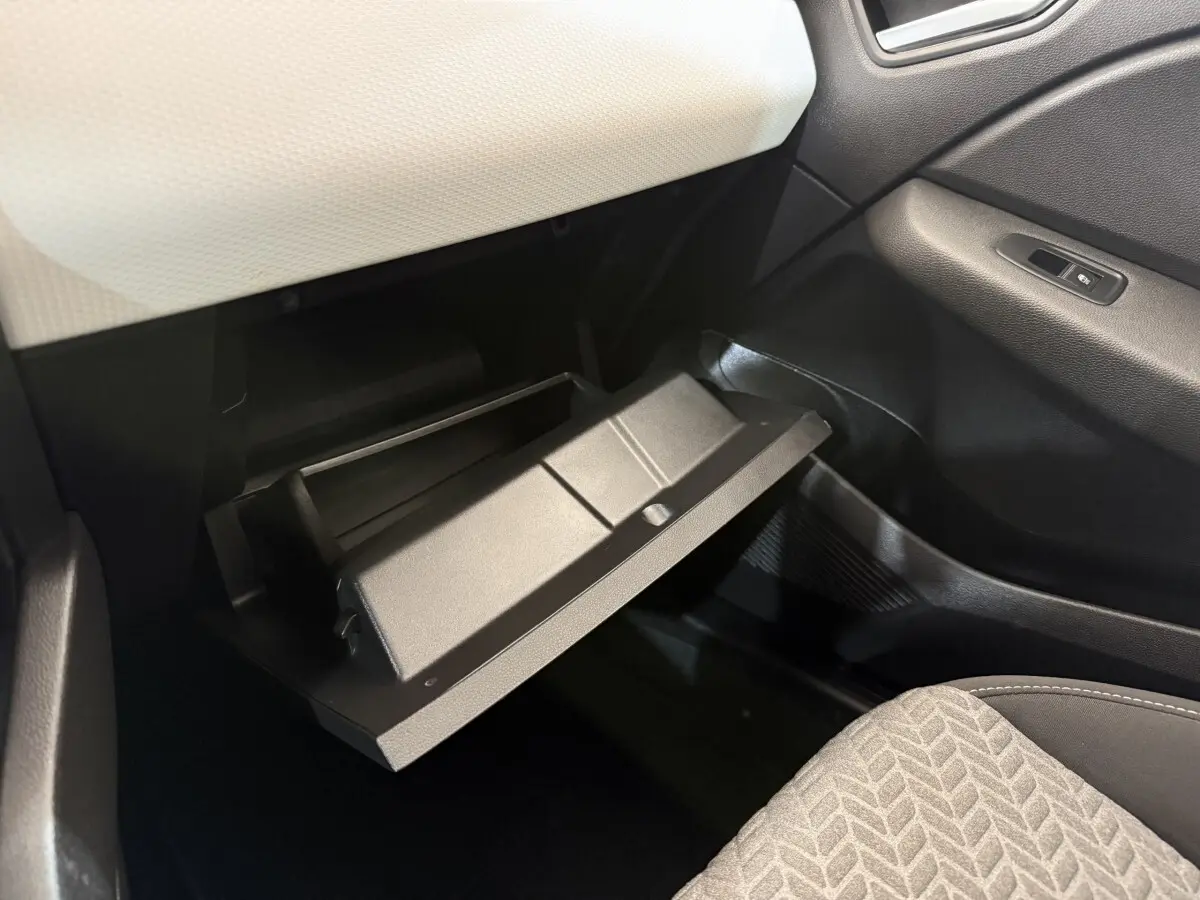 Vue intérieure côté passager de la Renault Clio 2023 avec boîte à gants ouverte et sellerie tissu gris.