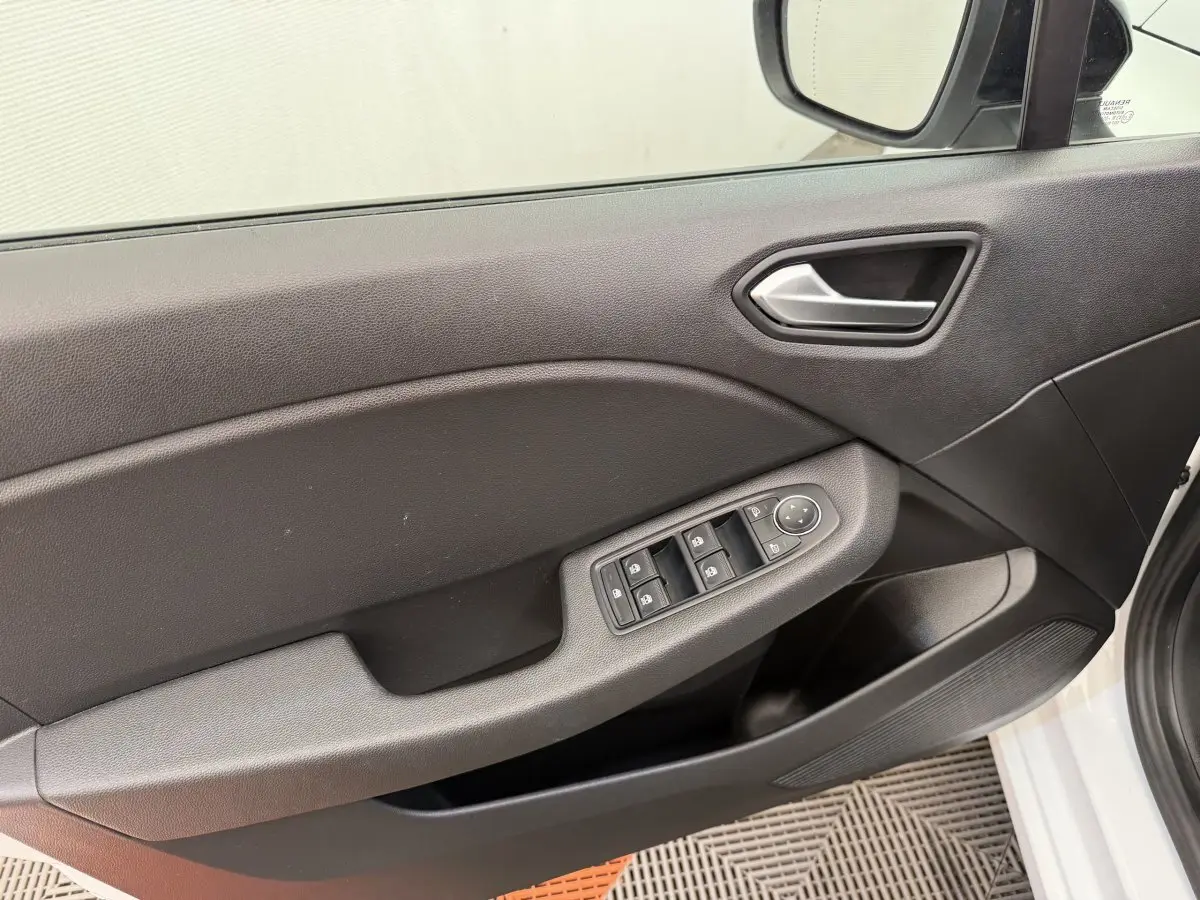 Vue intérieure du panneau de porte avant gauche de la Renault Clio blanche 2023, avec commandes électriques des vitres et rétroviseurs.