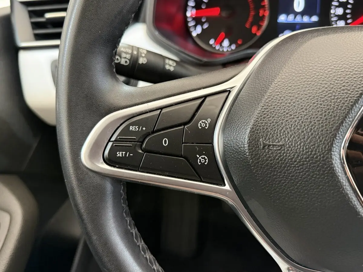Gros plan sur le volant cuir synthétique de la Renault Clio 2023 avec commandes de régulateur de vitesse visibles.