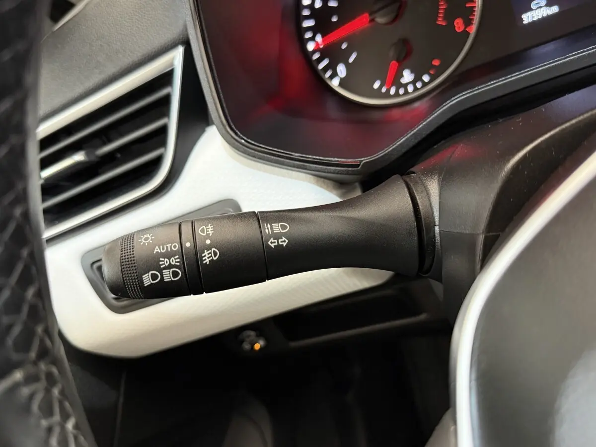 Gros plan sur la commande des feux et clignotants à gauche du volant dans une Renault Clio blanche 2023.