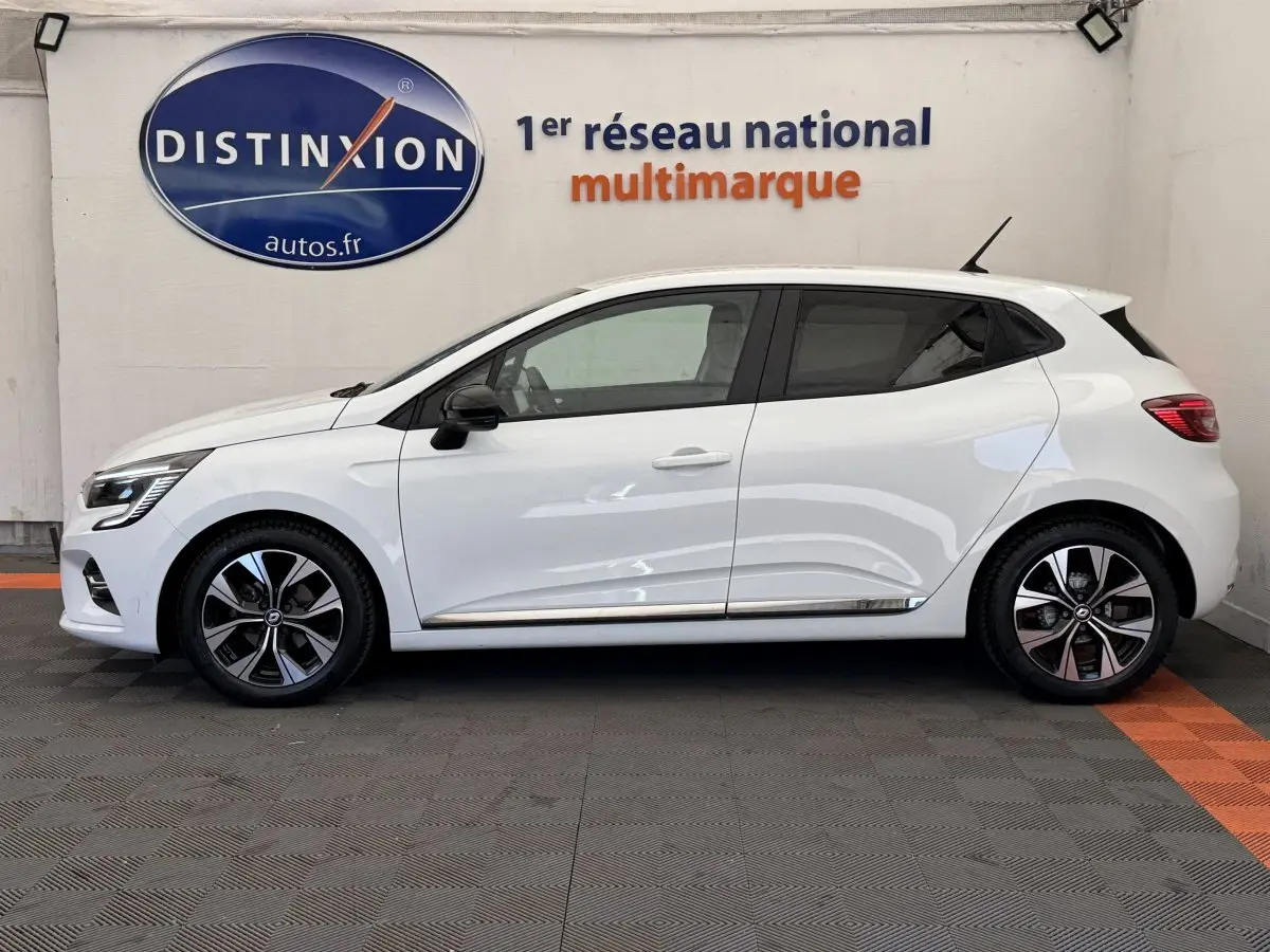 Profil côté gauche d'une Renault Clio Evolution TCe 100 GPL blanche, avec jantes alliage et vitres teintées.