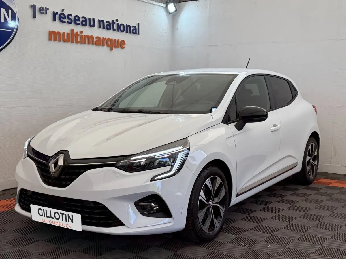 Renault Clio Evolution TCe 100 GPL blanc en 3/4 avant droit, avec jantes noires et détails noirs contrastants.