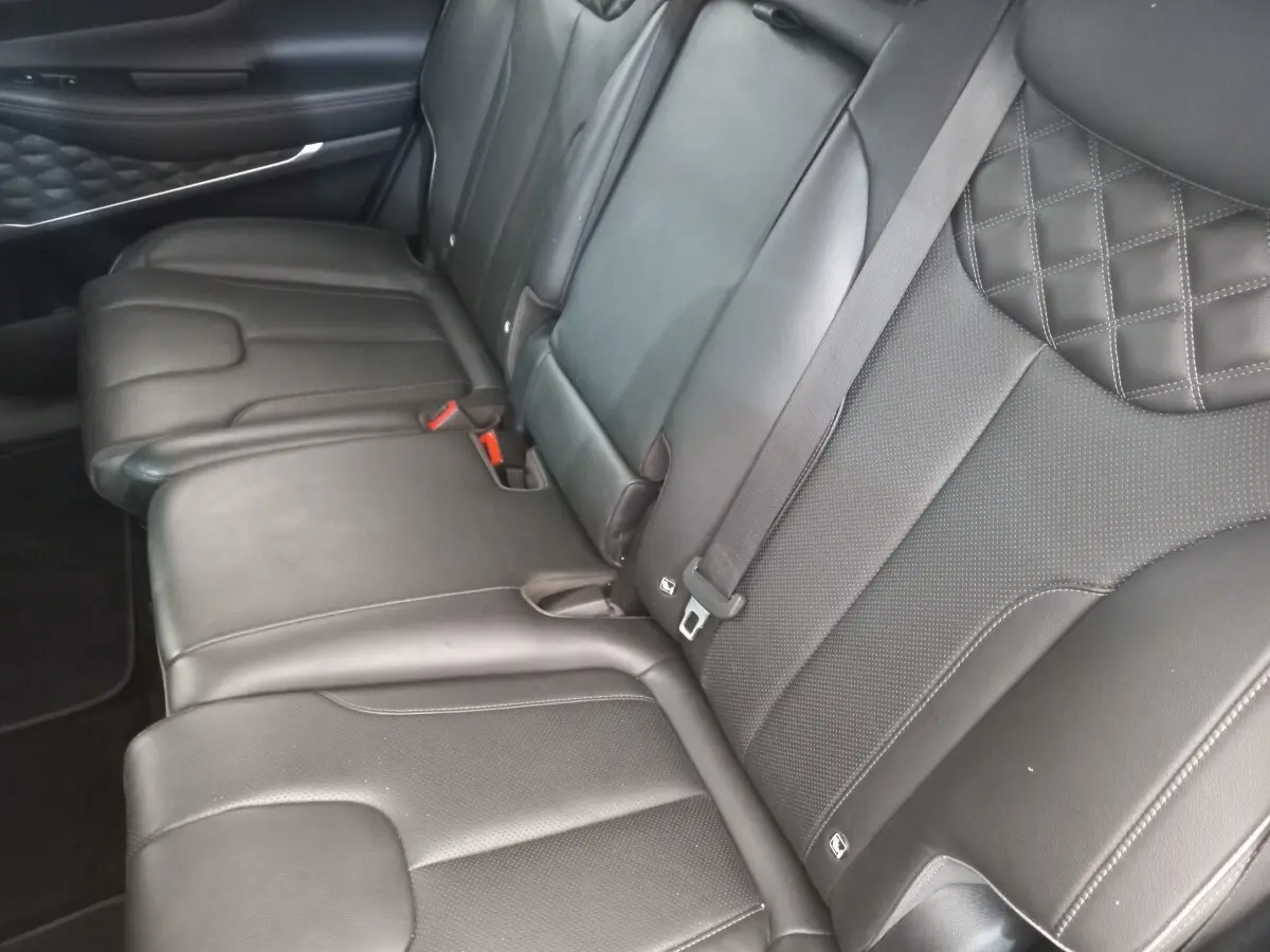 Vue rapprochée de la banquette arrière en cuir noir du Hyundai Santa Fe 2022 avec surpiqûres losanges et ceintures grises.