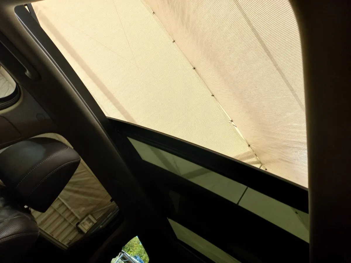 Vue intérieure du toit ouvrant en verre électrique du Hyundai Santa Fe gris clair, avec partie du siège avant en cuir visible.
