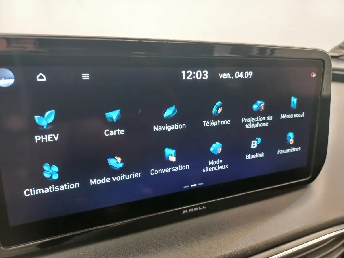 Écran tactile central du Hyundai Santa Fe gris clair, affichant le menu principal avec icônes bleues, vue intérieure.