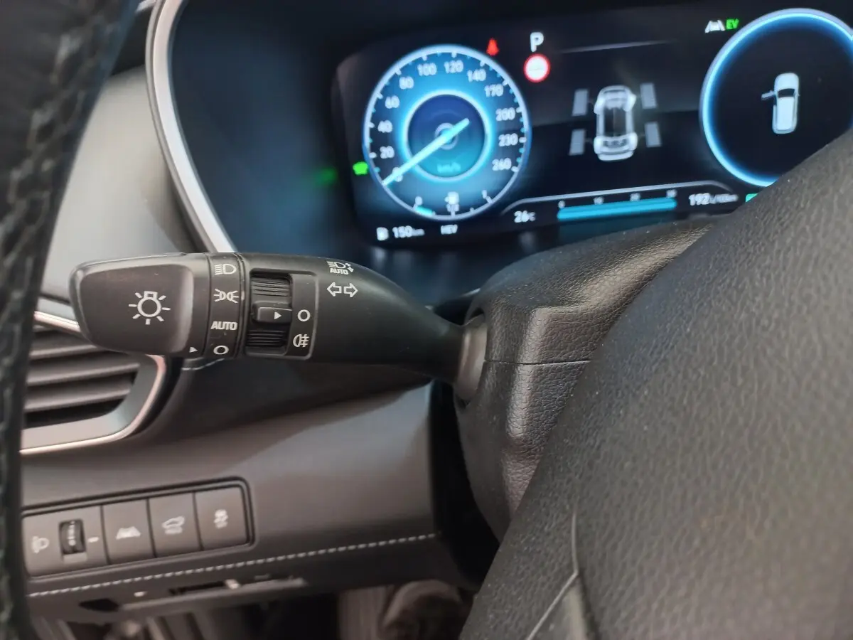 Détail du commodo des phares et clignotants côté gauche du volant cuir dans le tableau de bord numérique bleu du Hyundai Santa Fe gris clair 2022.