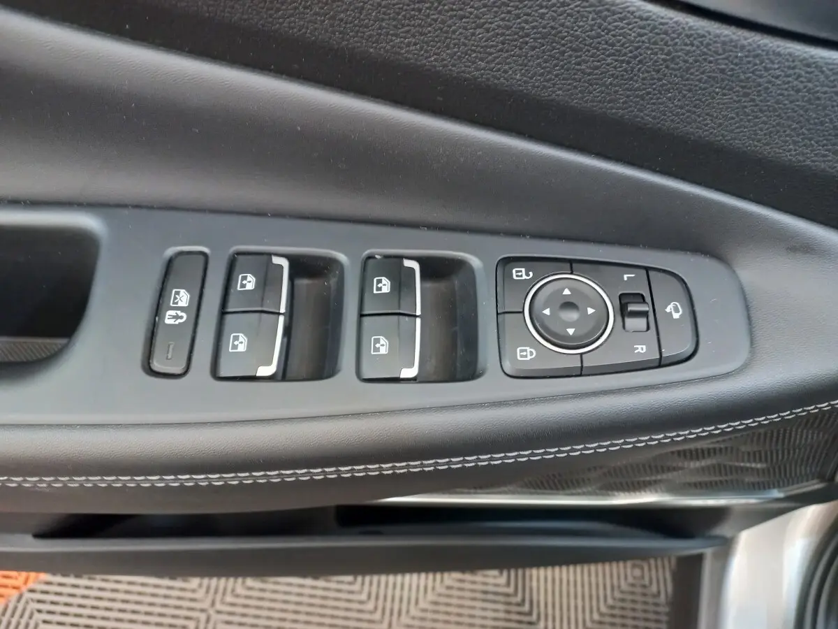 Gros plan sur les commandes de lève-vitres et réglage des rétroviseurs côté conducteur du Hyundai Santa Fe gris clair 2022.
