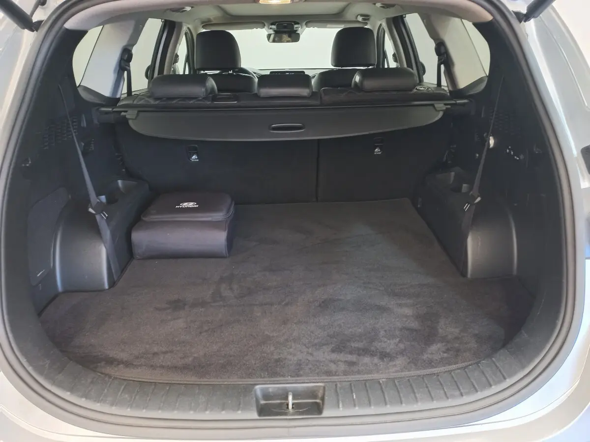 Coffre ouvert d’un Hyundai Santa Fe gris clair, montrant un espace de chargement propre avec cache-bagages noir.