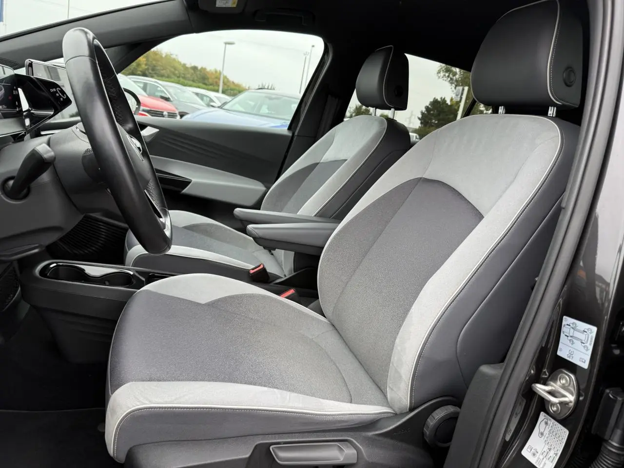 Vue intérieure côté conducteur du Volkswagen ID.3 Pro S 77 kWh 2022, sièges tissu gris clair et foncé avec accoudoirs.