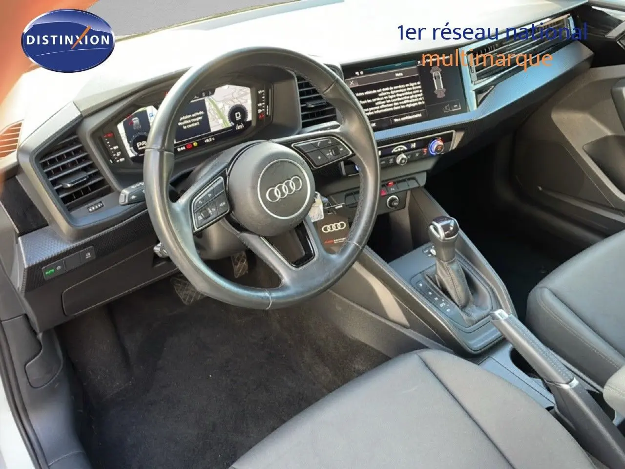 Vue intérieure de l'Audi A1 Sportback 2023 montrant le volant, tableau de bord numérique et levier de boîte auto.