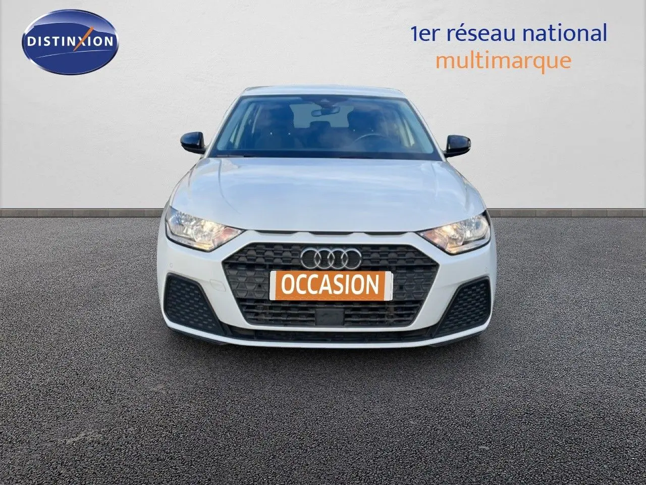 Audi A1 Sportback blanc glacier vue de face, mettant en valeur sa calandre hexagonale et ses phares LED allumés.