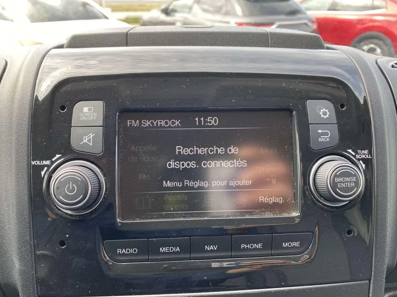 Vue rapprochée de l’écran multimédia noir du tableau de bord de l’Opel Movano Fourgon blanc, affichant la recherche de dispositifs connectés.