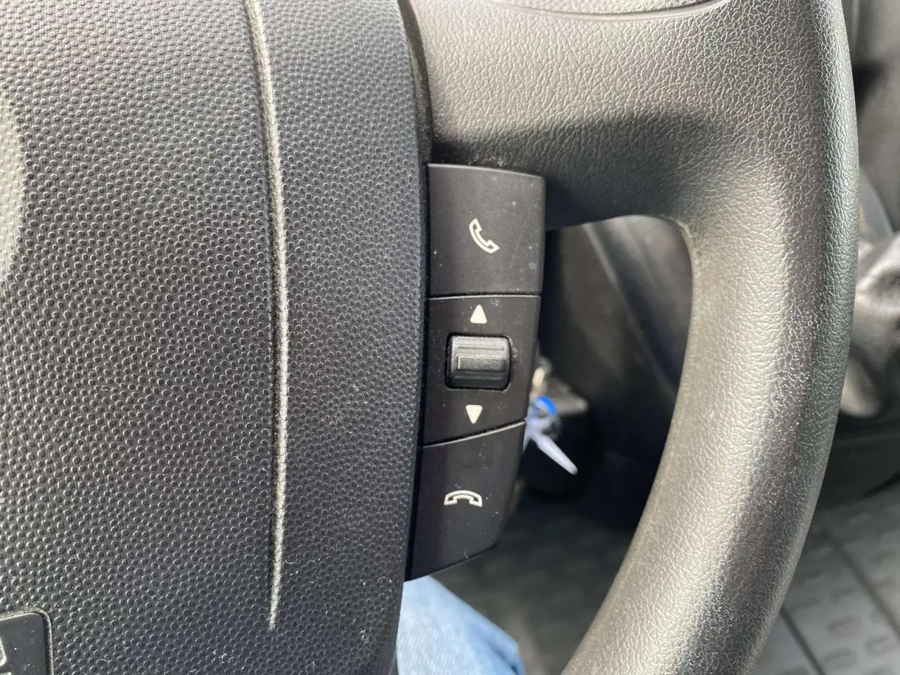 Gros plan sur les commandes téléphoniques au volant noir de l’Opel Movano Fourgon blanc de 2022.