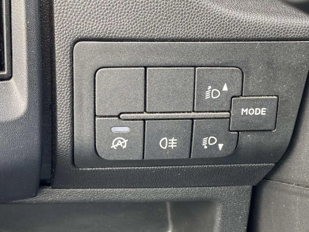 Panneau de commandes intérieures noires avec boutons de réglage des phares et mode sur Opel Movano Fourgon blanc.