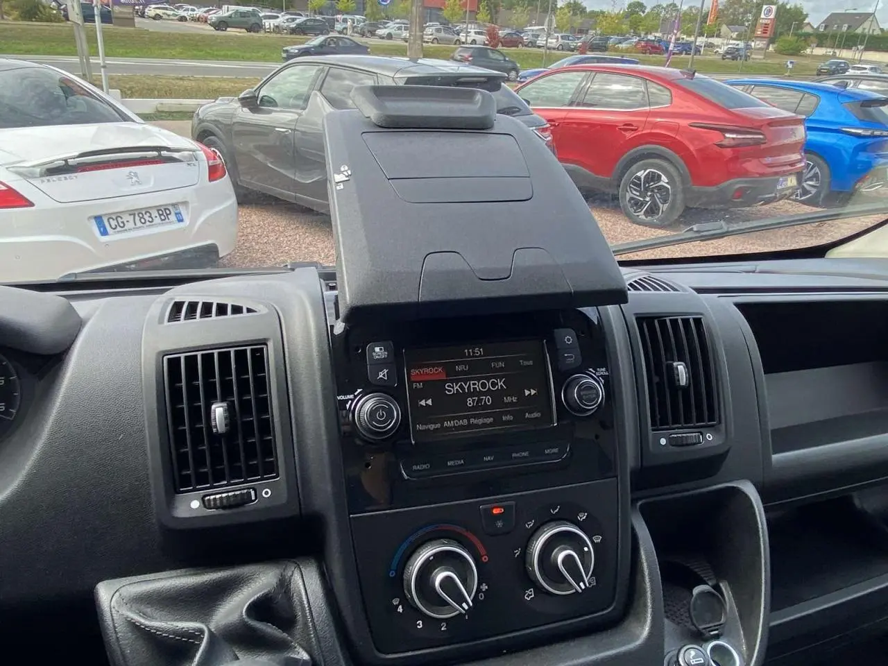 Vue intérieure centrée sur la console centrale de l'Opel Movano blanc, avec écran radio et commandes de climatisation visibles.