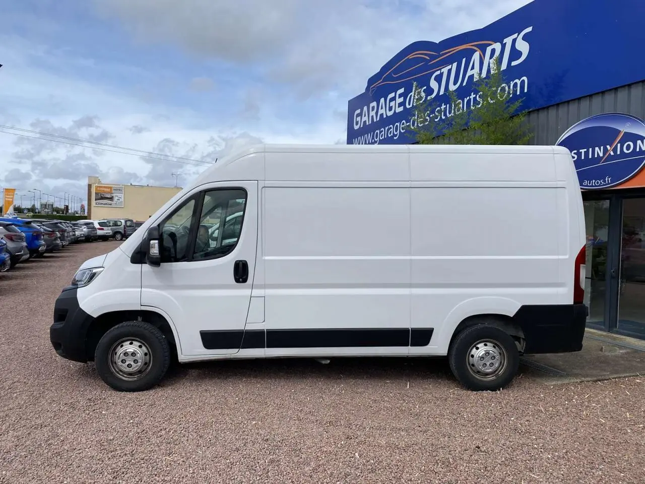 Vue de profil côté gauche d'un Opel Movano Fourgon blanc 2022 stationné devant un garage.