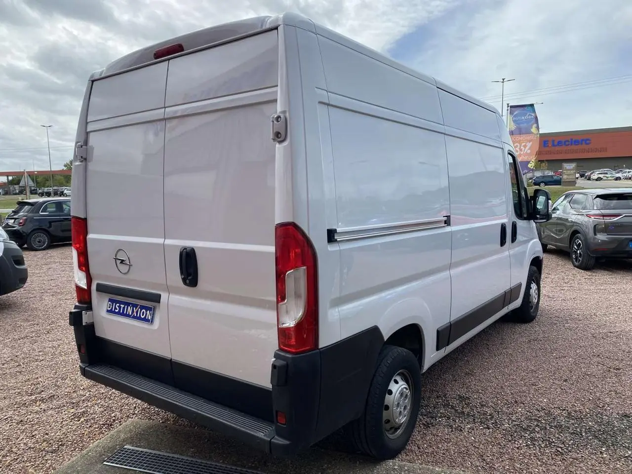 Vue 3/4 arrière droite d’un Opel Movano Fourgon blanc avec portes arrière battantes tôlées sur un parking.