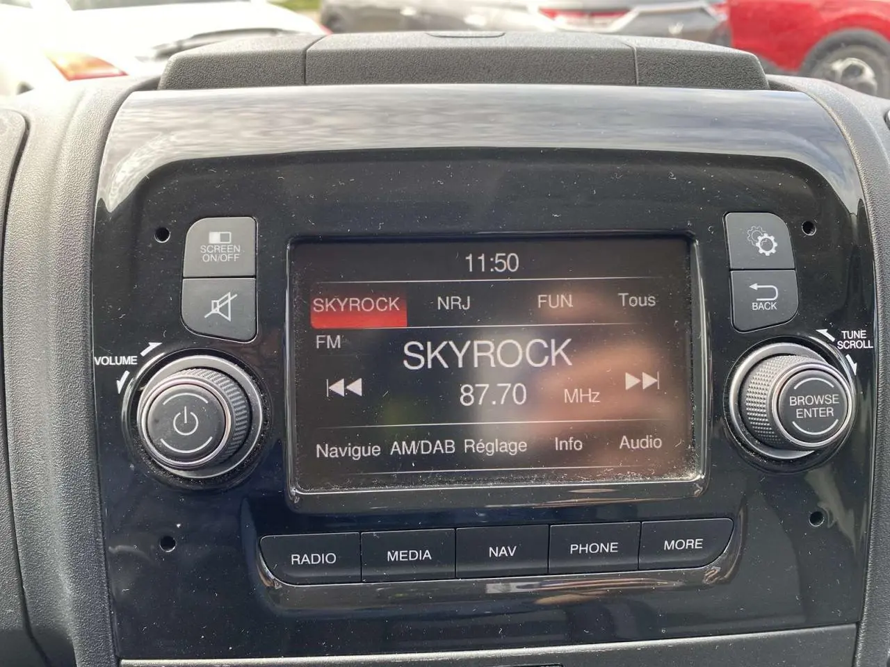 Gros plan sur l’écran multimédia noir du tableau de bord de l’Opel Movano Fourgon affichant la radio Skyrock.