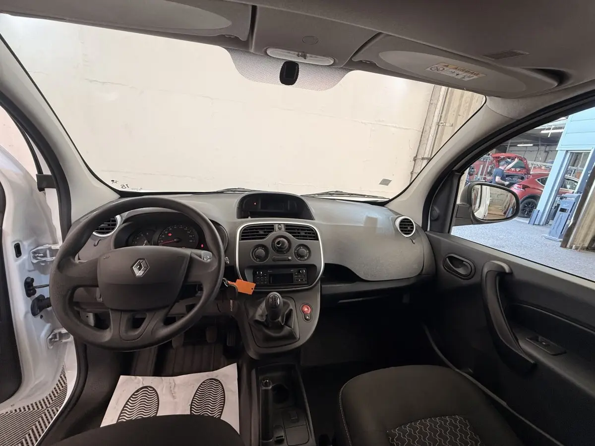 Intérieur avant du Renault Kangoo blanc 2016, vue côté conducteur avec volant, tableau de bord et levier de vitesses manuelle visibles.