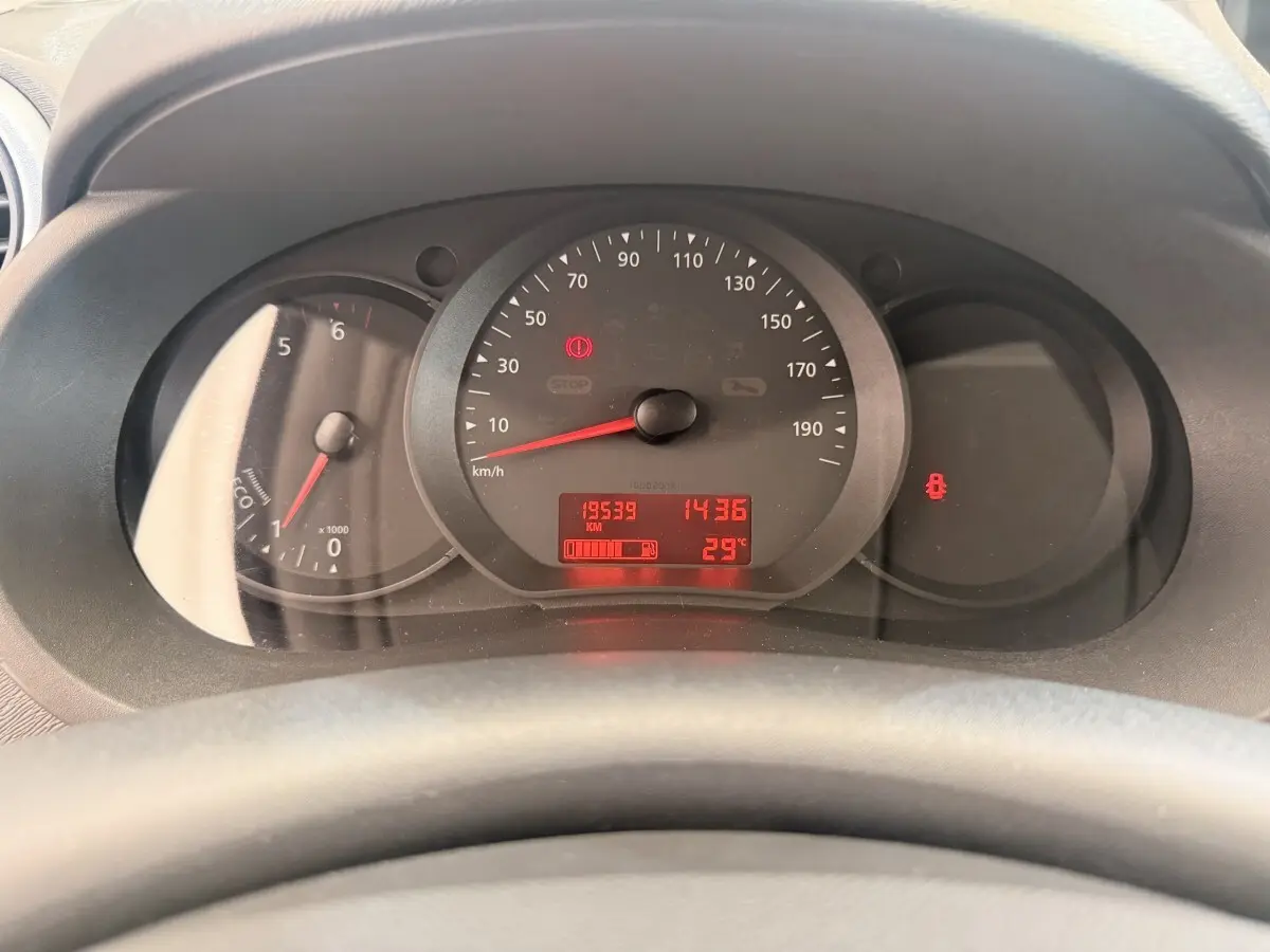 Vue rapprochée du tableau de bord du Renault Kangoo blanc, affichant le compteur et les voyants allumés.