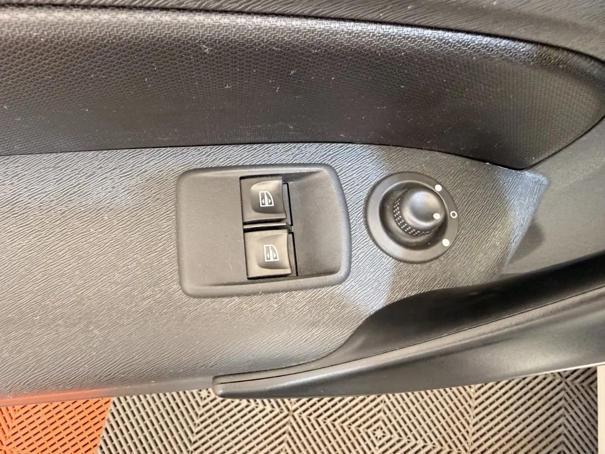 Détail des commandes de lève-vitres et réglage des rétroviseurs sur la porte côté conducteur d’un Renault Kangoo blanc.