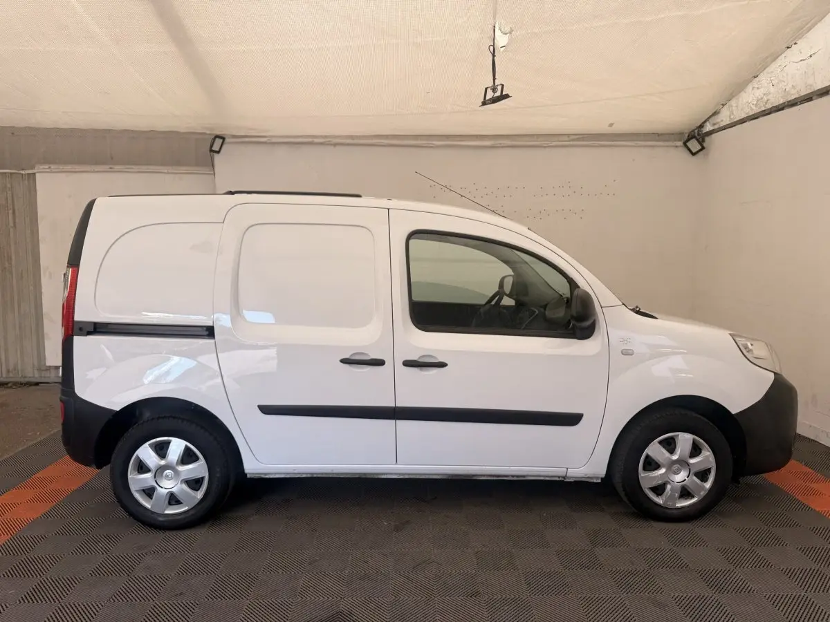 Profil droit d’un Renault Kangoo blanc 2016, utilitaire compact avec portes latérales et jantes acier.