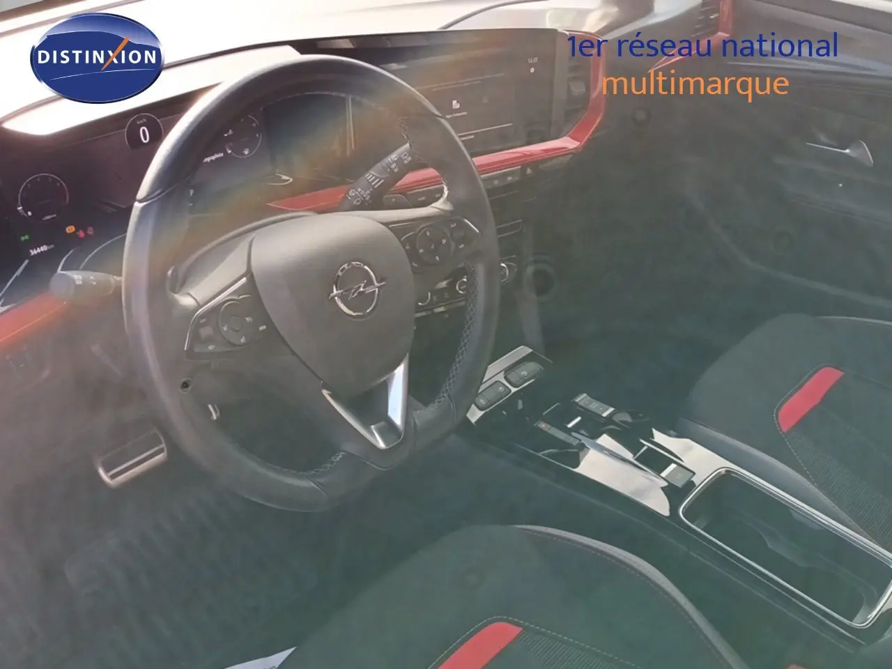 Intérieur de l'Opel Mokka GS Line 2022, vue du poste de conduite avec volant et console centrale noire et rouge.