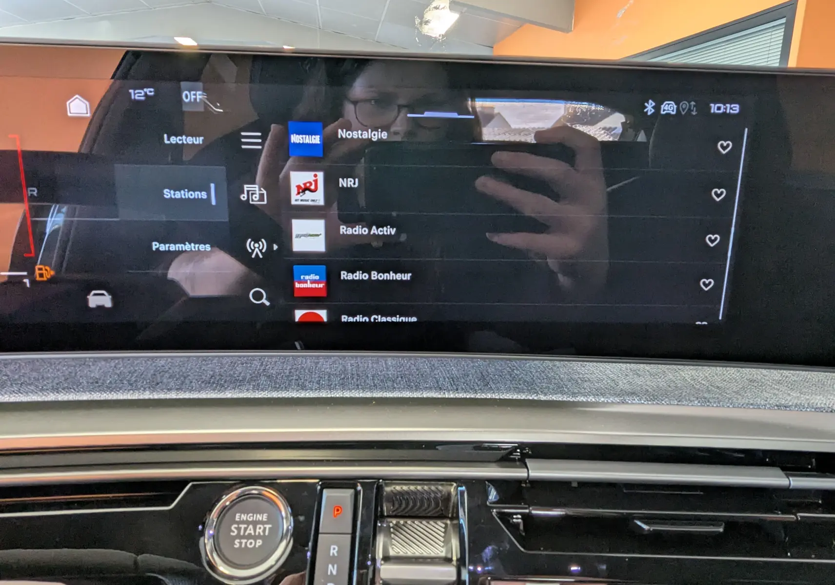 Vue intérieure du tableau de bord du Peugeot 3008 hybride 2026, écran tactile affichant les stations radio et bouton start/stop.