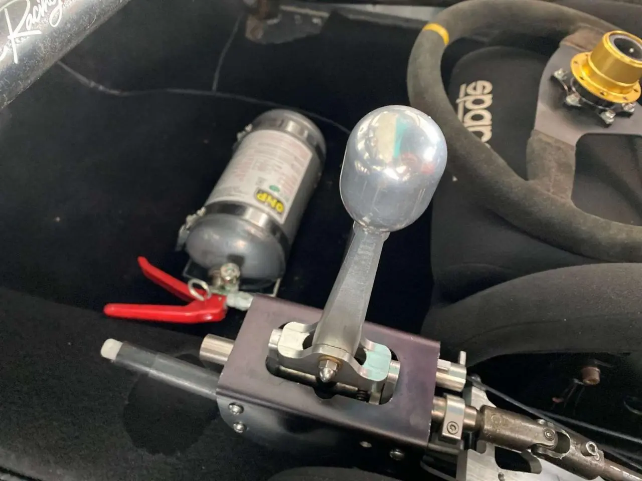 Gros plan sur le levier de vitesses manuel rigide et siège baquet Sparco noir dans l’habitacle d’une Porsche 911 gris métallisé.