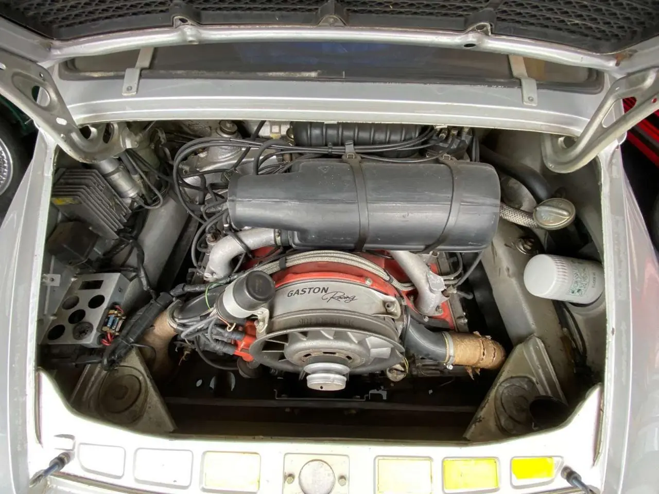 Vue plongeante sur le moteur arrière d’une Porsche 911 3.0 SC gris métallisé avec marquage Gaston Racing visible.