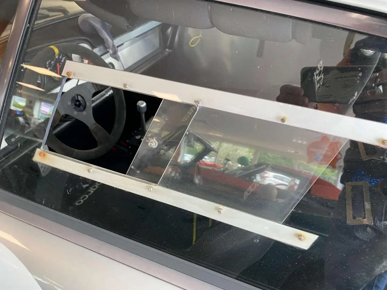 Vue intérieure côté gauche d’une Porsche 911 3.0 SC grise, montrant le volant Sparco et les baquets course.