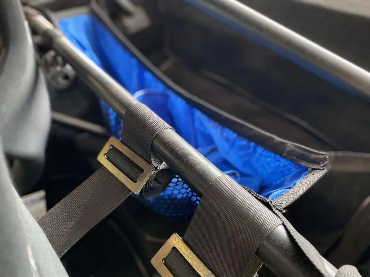 Détail intérieur montrant l’arceau cage tubulaire noir et le filet porte-paquets bleu sur Porsche 911 3.0 SC 1980 gris métallisé.
